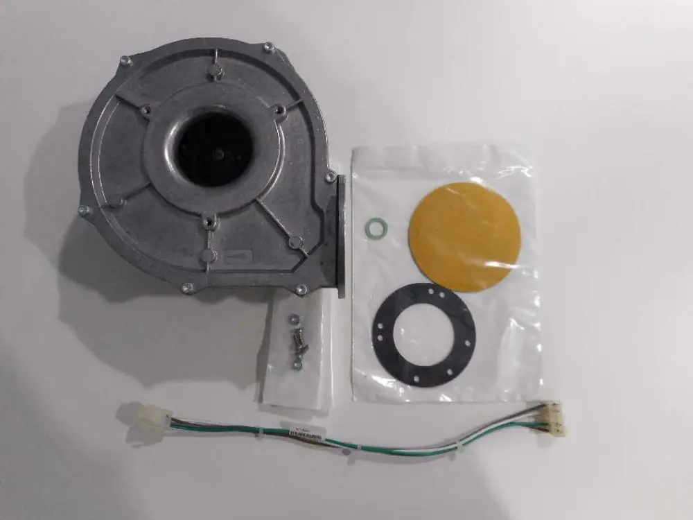 Gebläse von Remeha, metallisch mit Lüfteröffnung, einschließlich Dichtungen und Kabel. Zubehörteile in transparenter Verpackung auf hellem Hintergrund.
